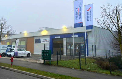 Création et pose d'une enseigne publicitaire, de drapeaux imprimés et décorations des véhicules pour un garage automobile par l'équipe Le point com'