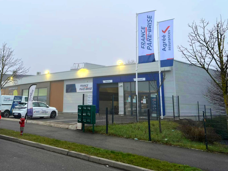 Création et pose d'une enseigne publicitaire, de drapeaux imprimés et décorations des véhicules pour un garage automobile par l'équipe Le point com'