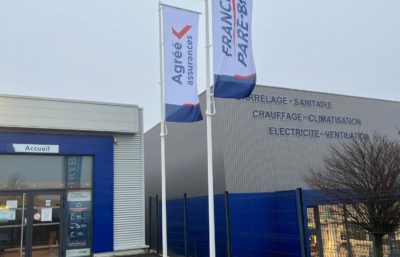 Création et pose de drapeaux imprimés pour un garage automobile par l'équipe Le point com'