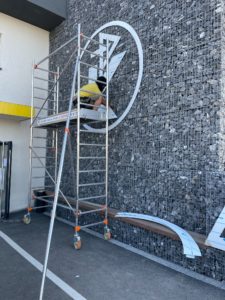 Réalisation de décoration de bâtiment et pose d'enseigne sur mur en pierre par l'équipe Le point com'