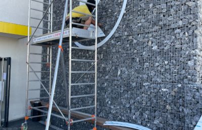 Réalisation de décoration de bâtiment et pose d'enseigne sur mur en pierre par l'équipe Le point com'